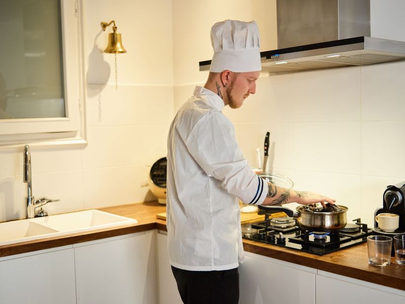 Private chef selecting fresh herbs in a vertically composed kitchen portrait